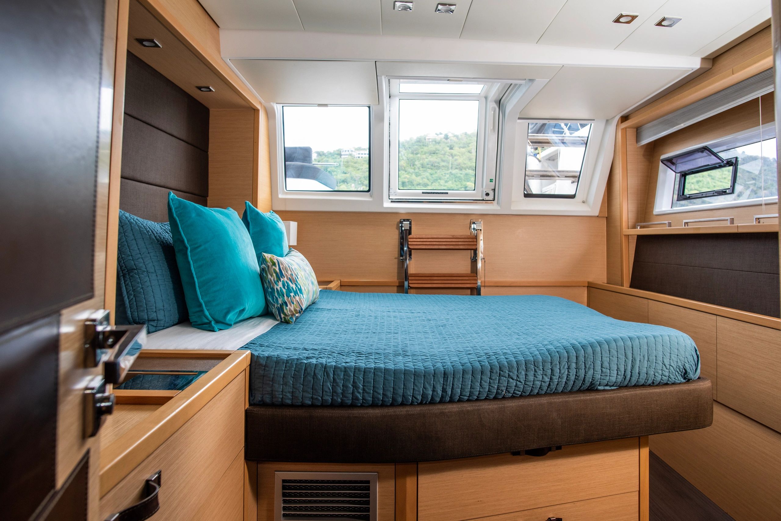 Ripple's queen-sized cabin with turquoise bedding and warm wood cabinetry