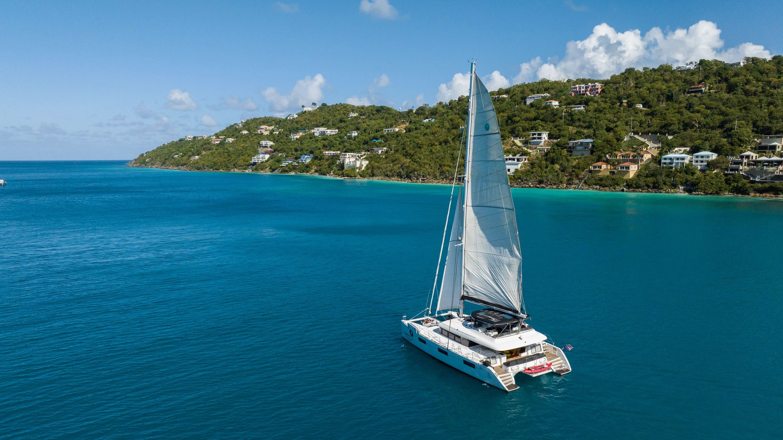 Aerial drone shot of Ripple anchored in crystal-clear turquoise bay